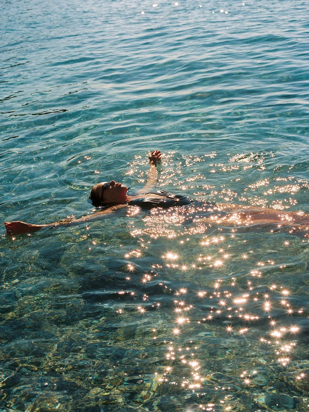 A swimmer floating in sparkling blue water