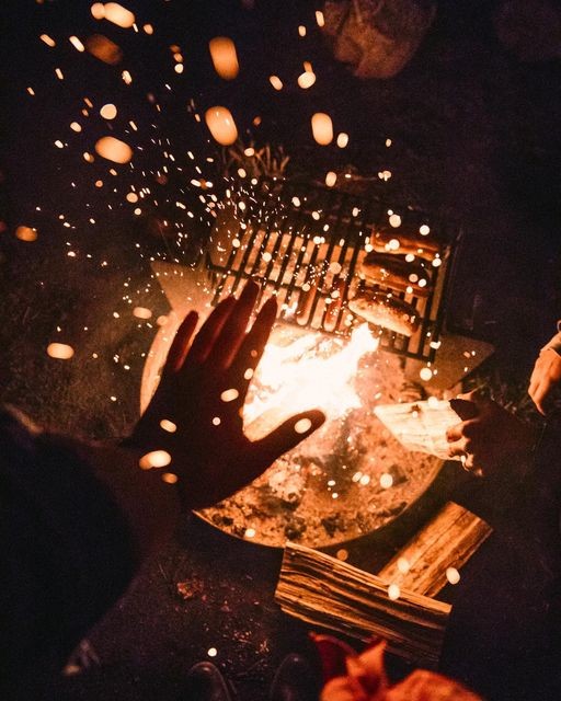 Hands held over a bright campfire
